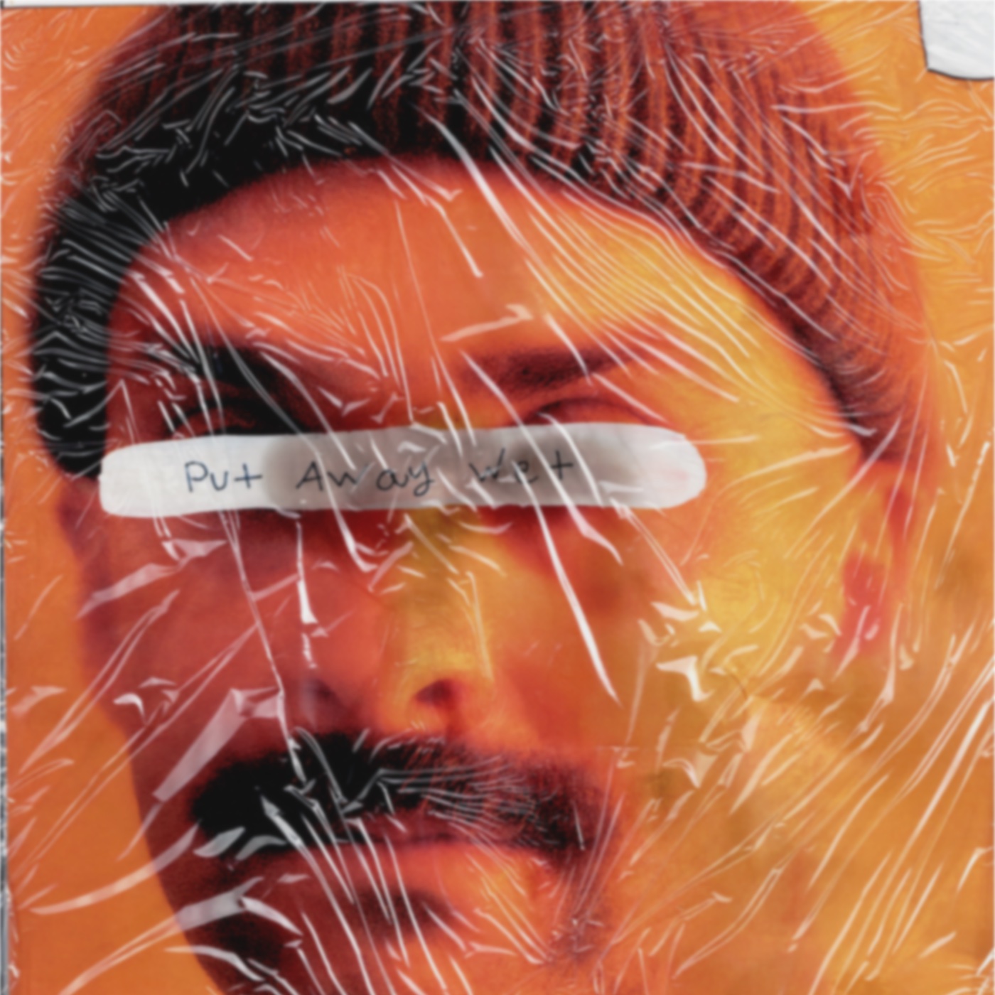 Put Away Wet cover: an orange portrait beneath scratched plastic, with the handwritten title across the eyes.